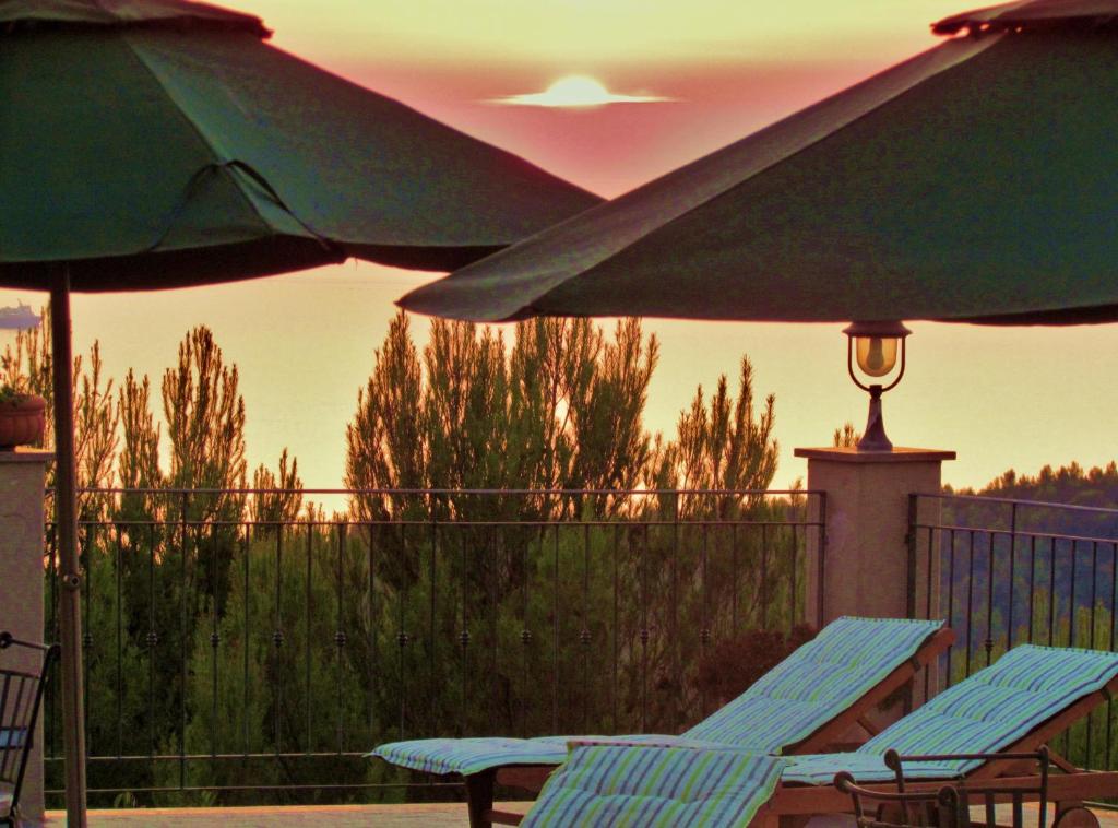 two chairs and umbrellas on a balcony with the sunset at Arpaderba B&B in Livorno