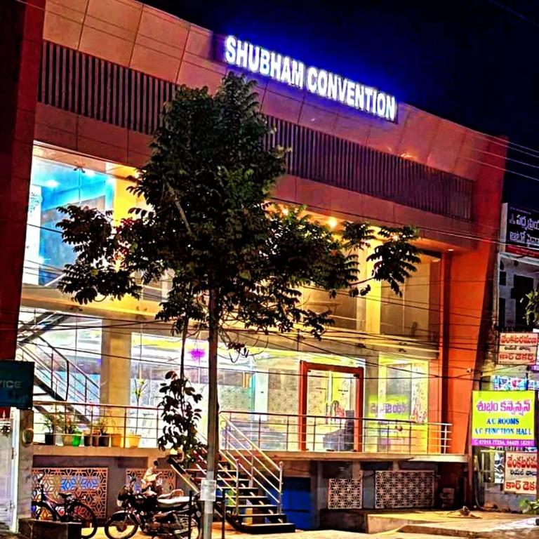 a building with a tree in front of it at Hotel Shubham in Karīmnagar