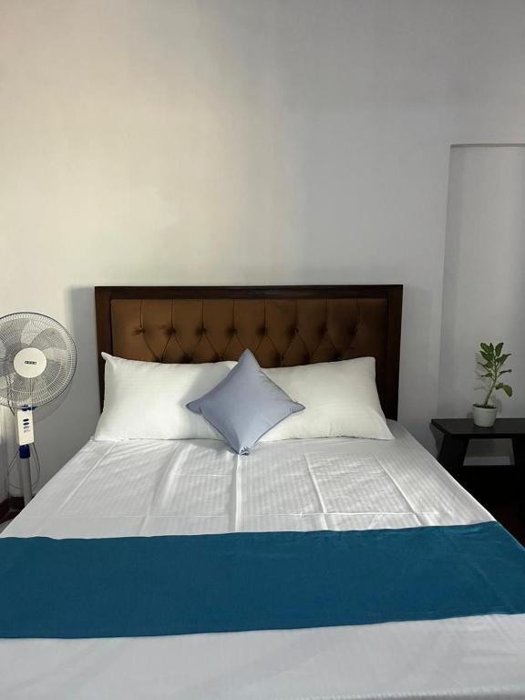 a bed with a blue and white pillow on it at Galeena Guest in Badulla