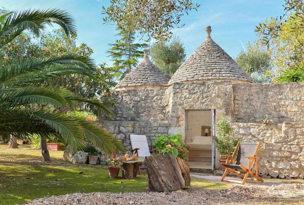 a stone building with a table and chairs in a yard at Trullo L'alcova in San Vito dei Normanni