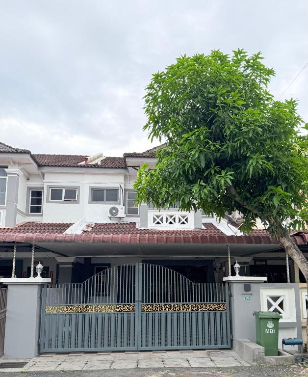 a house with a blue gate and a tree at Kings Park Homestay in Ipoh