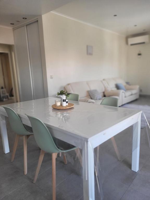 a white dining table with green chairs in a living room at Oeiras Historic Bedrooms in Oeiras