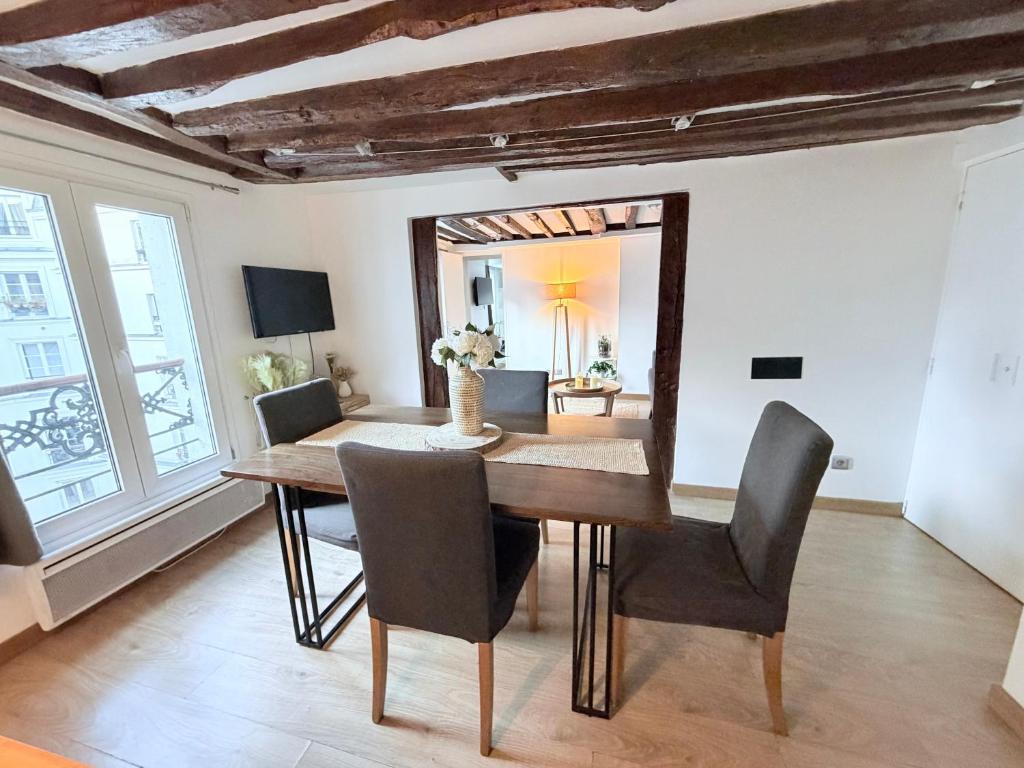 a dining room with a table and chairs and a mirror at Superbe Appartement in Paris