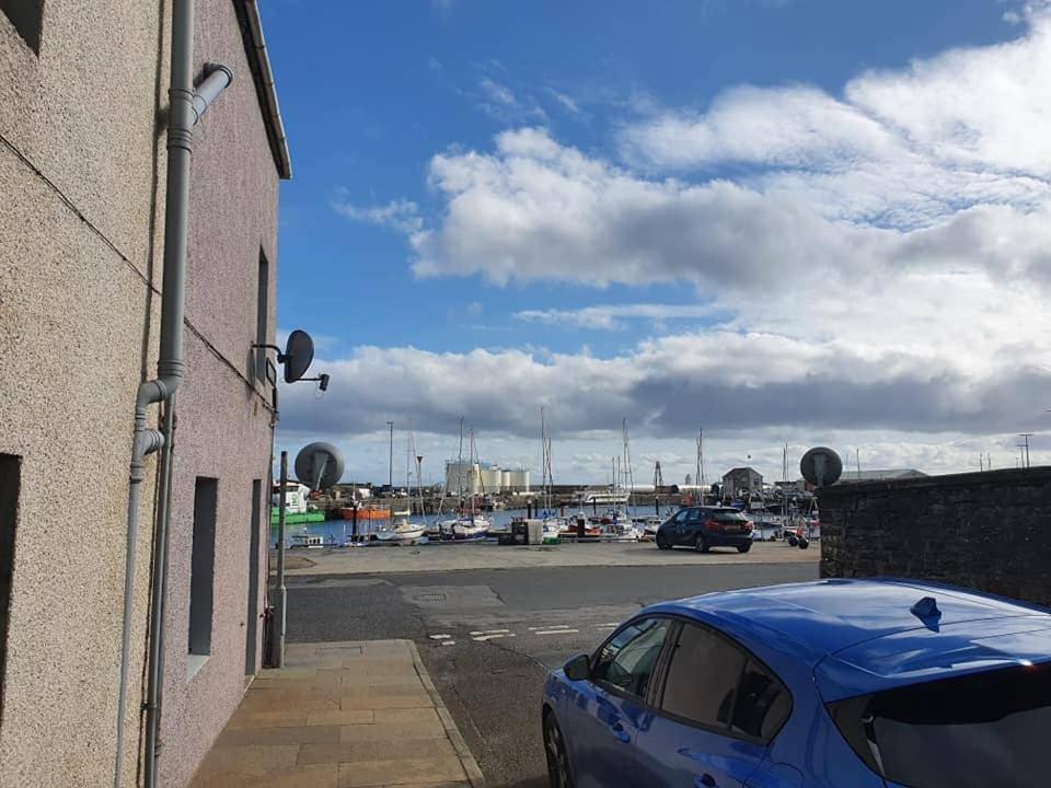 a blue car parked next to a building with a parking lot at Spacious 2 Double Bedroom House Wick Harbour in Wick