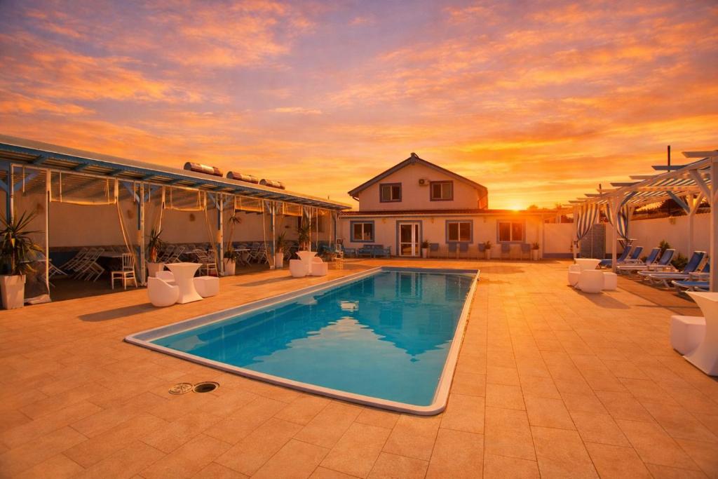 a swimming pool with a sunset in the background at Poseidon Jurilovca in Jurilovca
