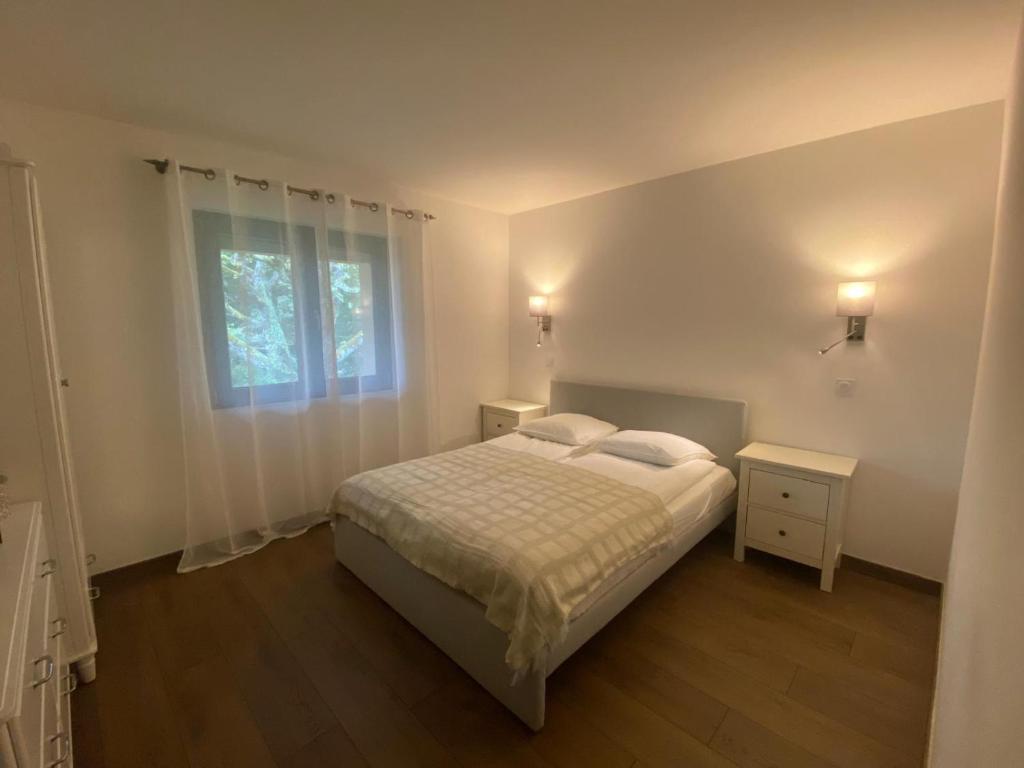 a white bedroom with a bed and a window at Pepy & Delmis in Chens-sur-Léman