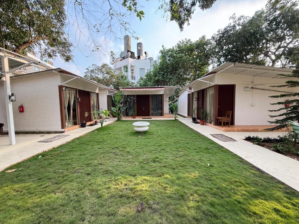 a backyard of a house with a grass yard at Anexx Goa in Vagator