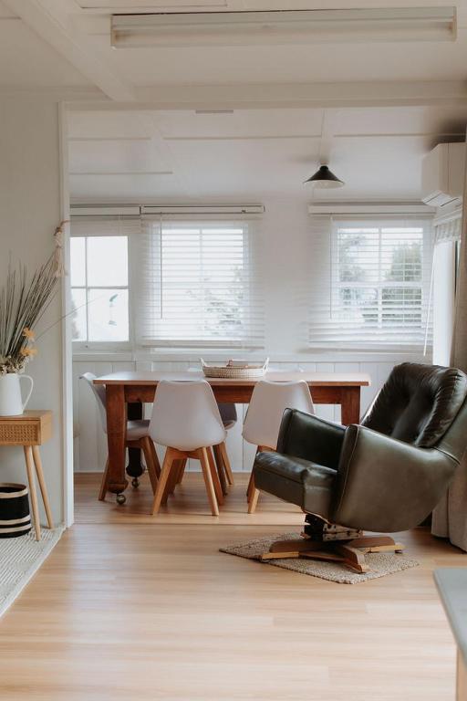a living room with a leather chair and a table at Pine Cottage in Dennes Point