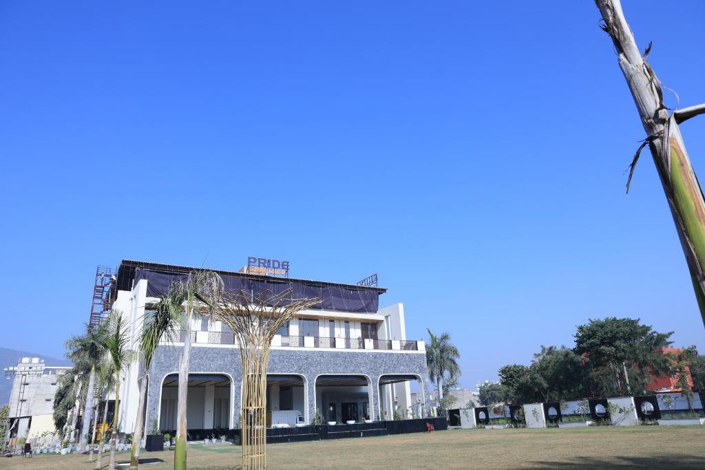 a white building with palm trees in front of it at Pride Premier Alwar - Sariska in Alwar
