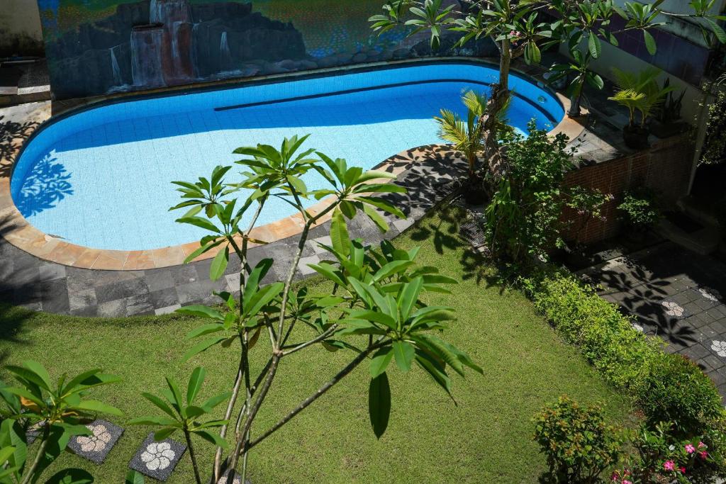 a swimming pool in a garden with trees and plants at Nusa Dua Moon Hotel in Nusa Dua