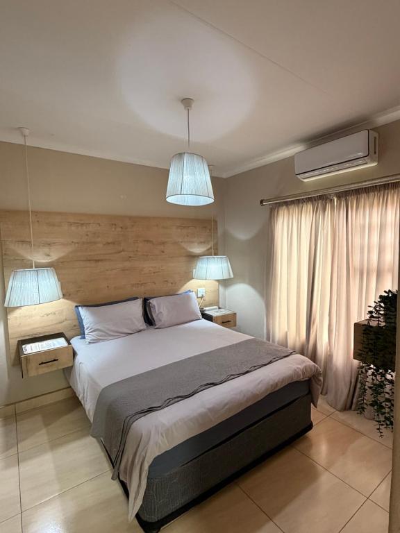 a bedroom with a bed with two lamps and two tables at On Smook in Zeerust