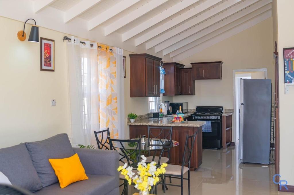 a living room with a couch and a kitchen at Colbeck sunshine oasis in Old Harbour