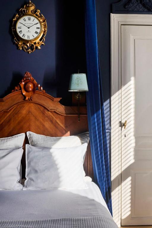 a bedroom with a bed with a clock on the wall at Maison d'Artiste in Ghent