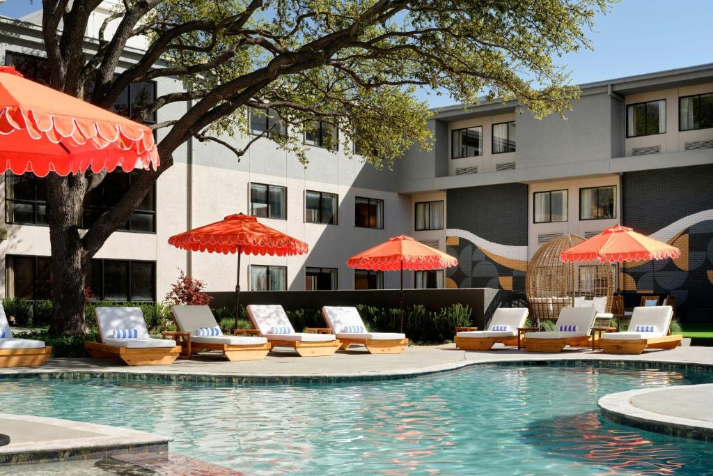 a swimming pool with lounge chairs and umbrellas at Hotel Dax in Addison