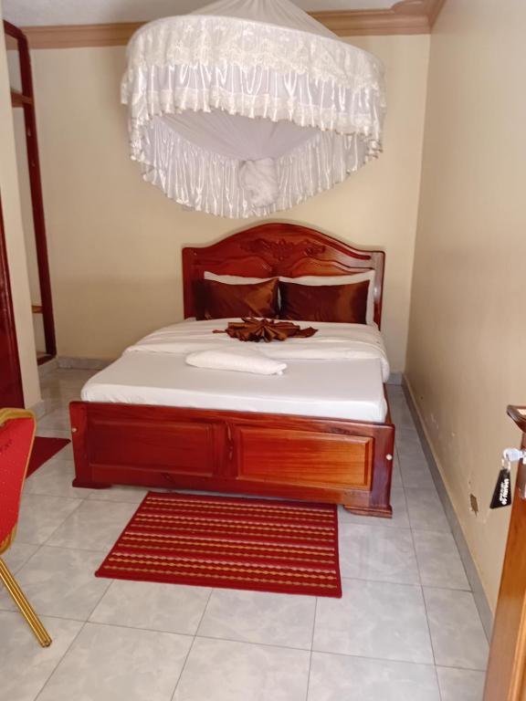 a bedroom with a bed with a wooden headboard at Uhuru 50 Hotel in Kasese