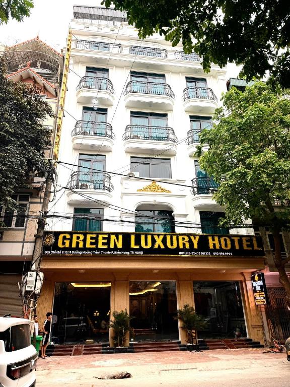 a white building with a green luxury hotel sign on it at Green Luxury Hotel in Hà Ðông