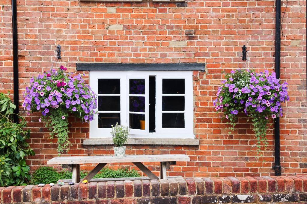 a picnic table in front of a brick building with flowers at The Ash Tree in Ashendon