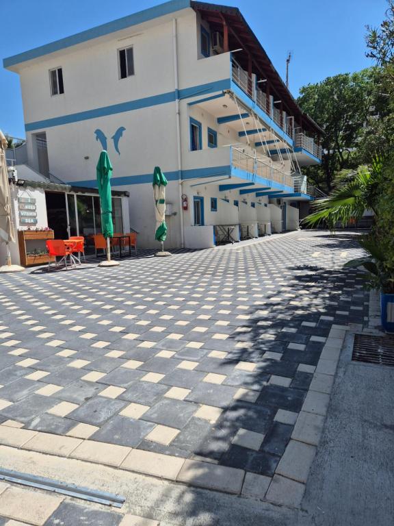 a building with a tiled sidewalk in front of a building at Rooms and Apartments Analipsi in Shëngjin