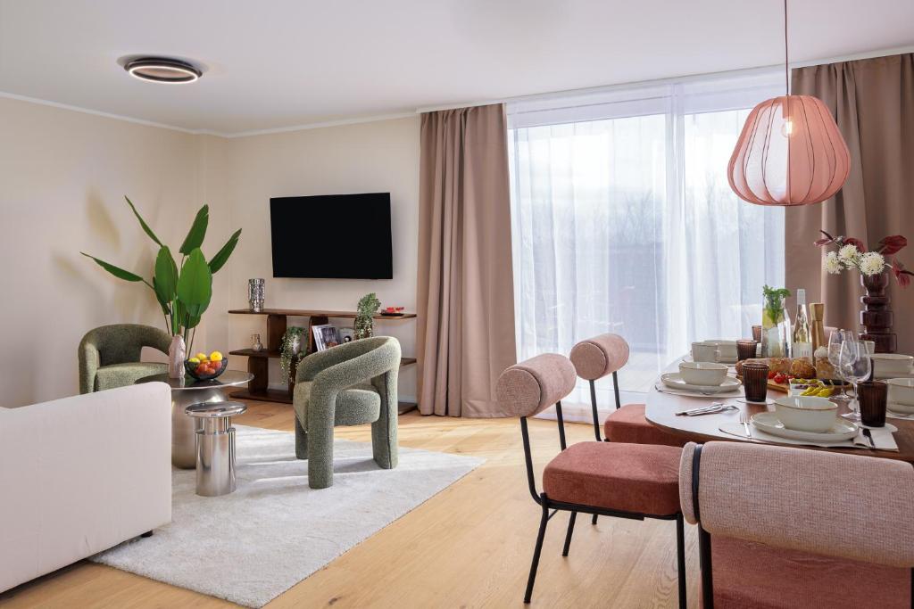 a living room with a table and chairs and a television at PLEIB COLOGNE - Premium Suites in Cologne