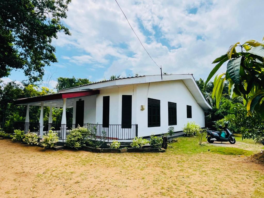 a small white house with black shuttered windows at Pudam Cottege in Kataragama