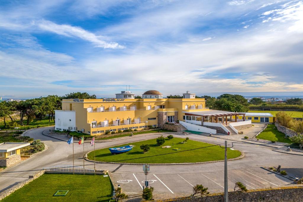 ein großes gelbes Gebäude mit einem Park davor in der Unterkunft Hotel Pinhal Mar in Peniche