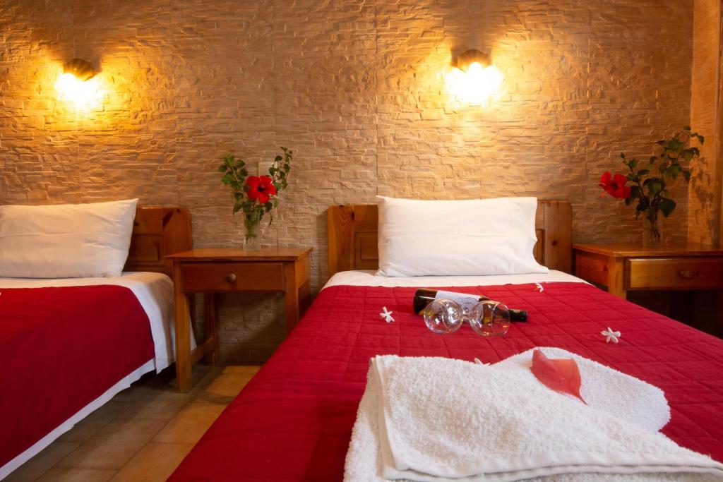 a bedroom with two beds with red sheets and flowers at G&P Rooms Matala in Matala