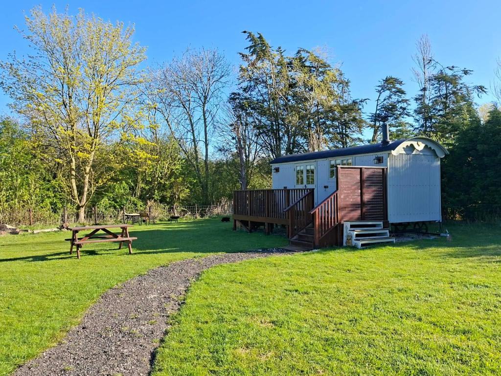 a tiny house in a field with a picnic table at Woodpecker Shepherds Hut in Boston