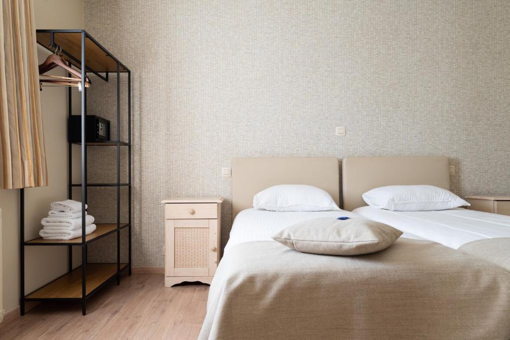 ein Schlafzimmer mit zwei Betten und einem Spiegel in der Unterkunft Hotel Amary in Maldegem