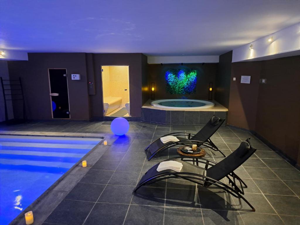 a room with a pool and chairs and a room with a tub at Suites et Wellness des Champs-Elysées in Ciney