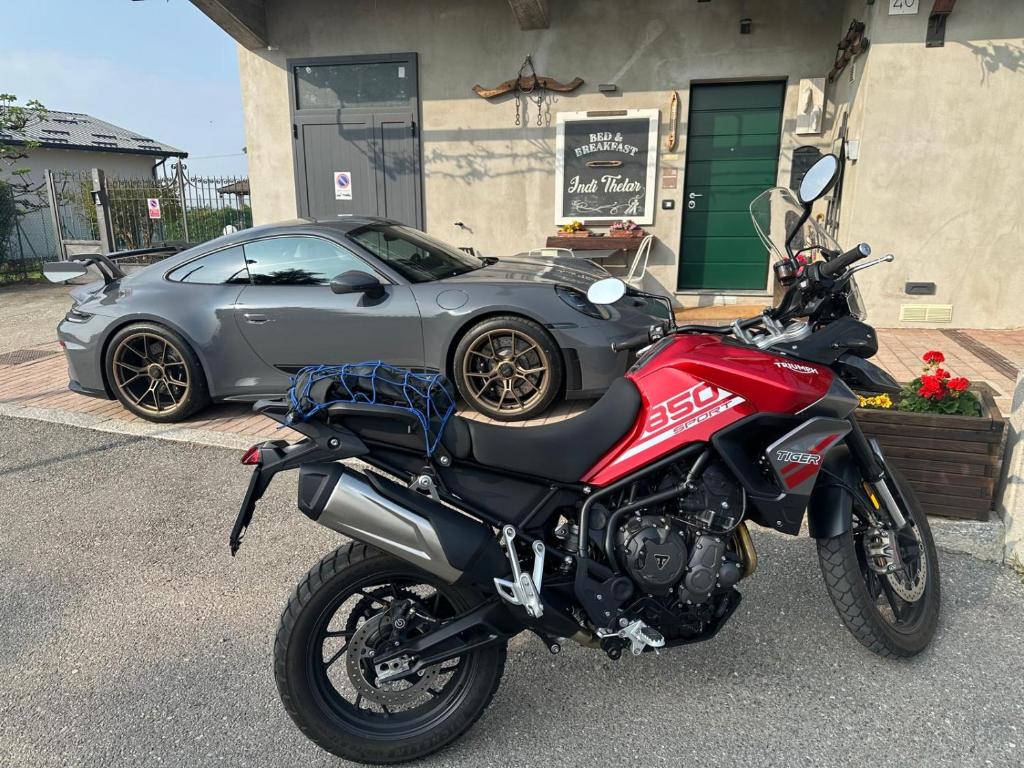 a red motorcycle parked in front of a car at Bed & Breakfast Indi Thelar in Villa Guardia