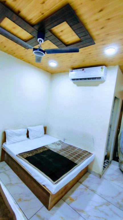a bed in a room with a wooden ceiling at Jay shree Kedar room in Ujjain
