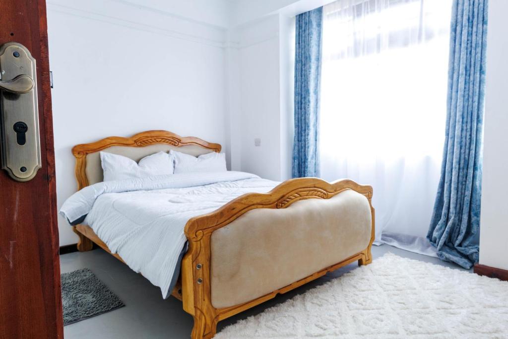 a bedroom with a bed with a wooden frame and a window at Pearl Homes Nanyuki in Nanyuki