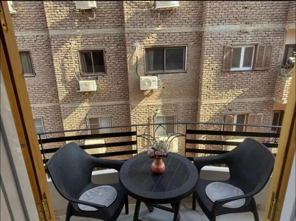 a balcony with a table and chairs and a building at Fatah O 9 in Luxor