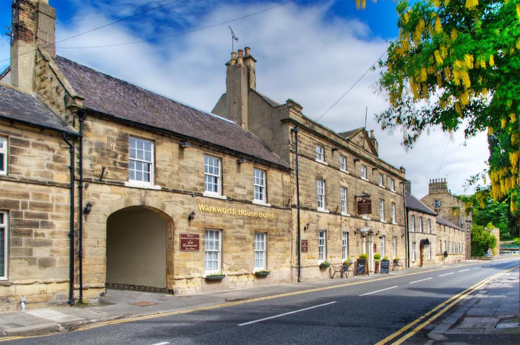 um antigo edifício de pedra ao lado de uma rua em Warkworth House Hotel em Warkworth