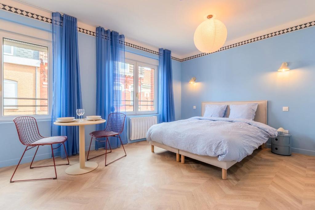 a blue bedroom with a bed and a table and chairs at Le Cottage du Louvre in Lens