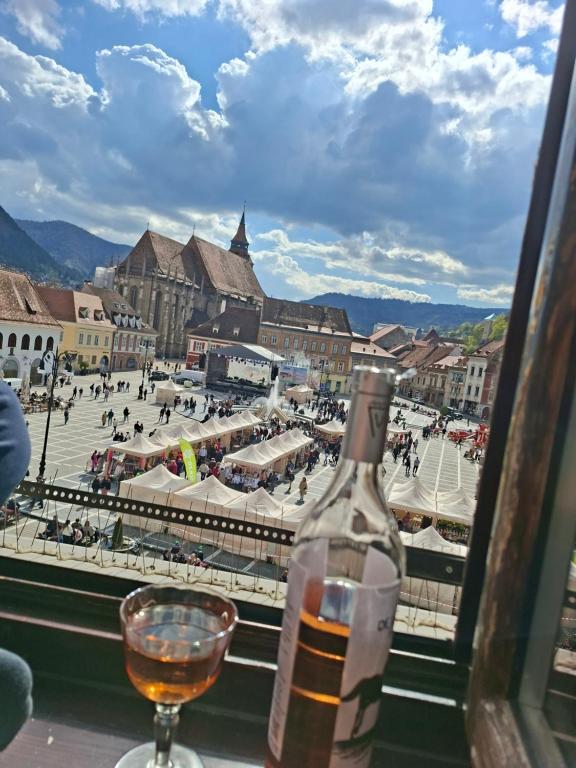 a bottle of wine and a glass on a window at Central View Piata Sfatului 7- Panoramic Apartment in Braşov