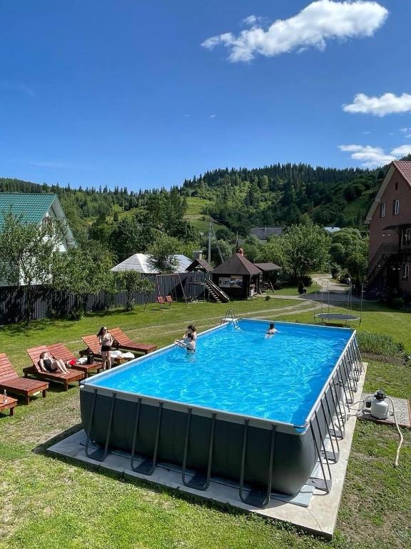 a large swimming pool in a yard with people in it at Тростян та річка in Slavske