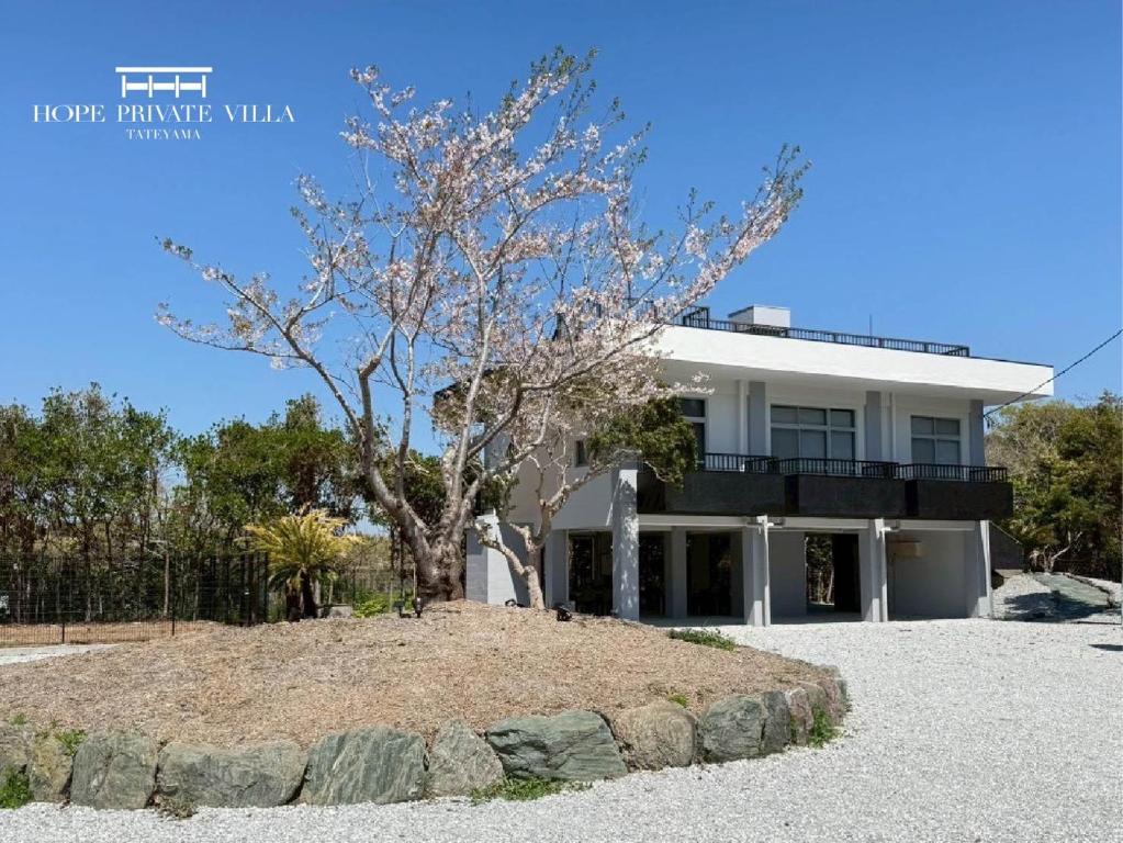 a white house with a tree in front of it at Hope Private Villa tateyama in Tateyama