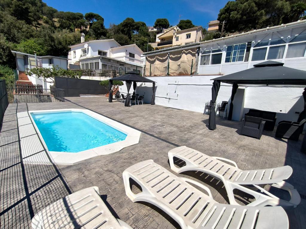 a swimming pool with two lounge chairs and a gazebo at Espacio Kybalion in Argentona