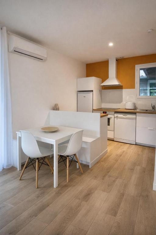 a kitchen with a white table and chairs at La Cachette du Lac-Douce parenthèse en famille près du lac & piscine in Lacanau