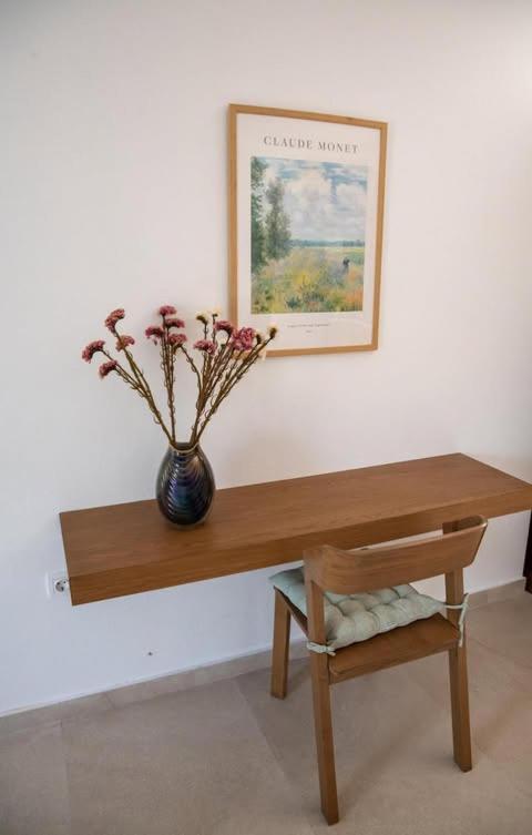 a wooden table with a vase of flowers on a wall at Agnanti in Agia Fotini