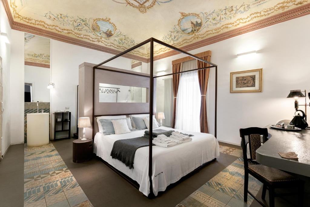 a bedroom with a canopy bed and a desk at Iblainsuite in Ragusa