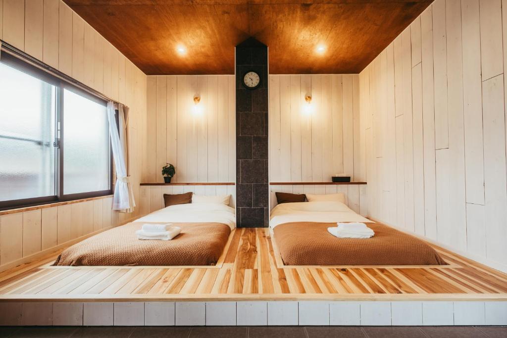 two beds in a room with a clock on the wall at 民泊やまねこ in Yachi
