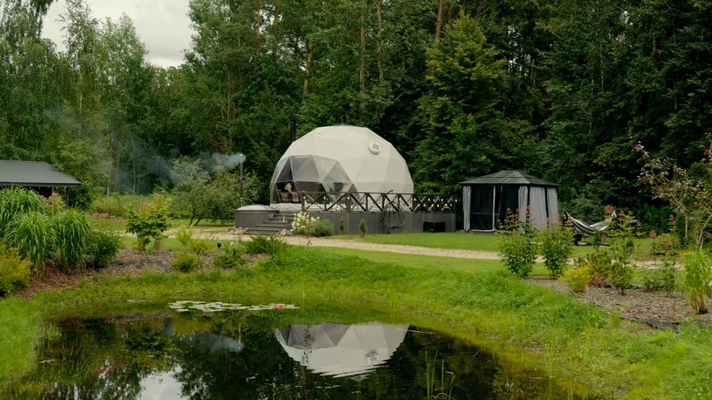 a dome tent in a garden next to a pond at Līgo glamping in Stacija Meitene