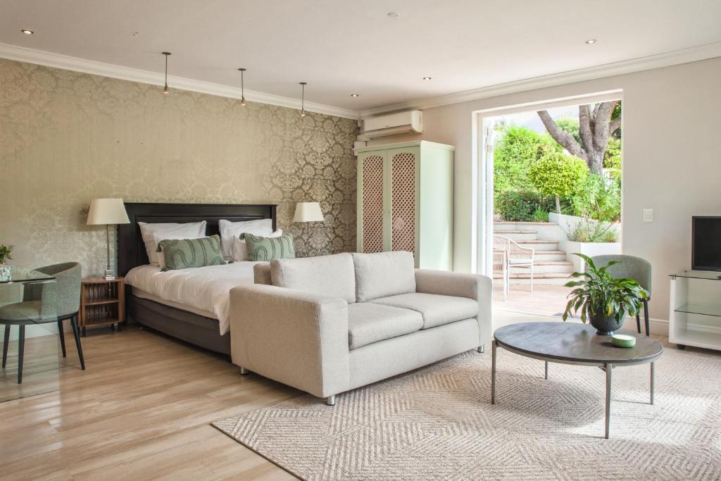 ein Schlafzimmer mit einem Bett, einer Couch und einem Tisch in der Unterkunft Francolin Studio in Kapstadt