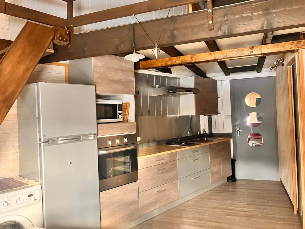 a kitchen with stainless steel appliances and wooden cabinets at Le Cercle des Neiges Étoilé in Métabief