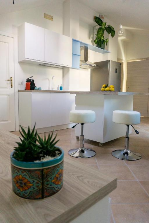 a kitchen with two stools and a kitchen with white cabinets at Nosside & Saffo Guesthouse in Amantea