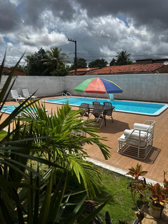 a pool with a table and an umbrella and chairs at Pousada Caju - Barreirinhas - Lençóis Maranhenses - Hotel in Barreirinhas