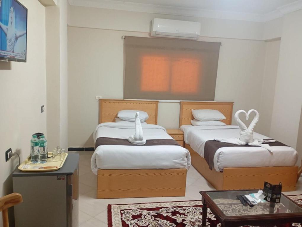 a hotel room with two beds and a table at فندق شهرزاد - Shahrazad Hotel in Banī ‘Aţīyah