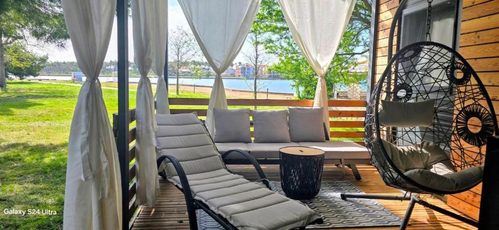 a porch with chairs and a couch and a table at SAK Mobile Home Privlaka in Privlaka